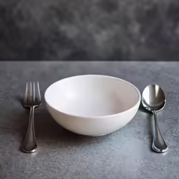 spoon, fork and bowl sitting next to each other on top of a table
