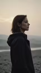 a young woman with a ponytail wearing a hoodie on the beach