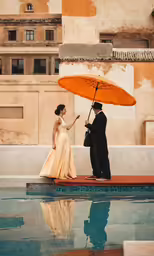 a man and a woman standing near each other holding an orange umbrella