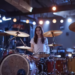 an asian girl is on the drum set while she plays it
