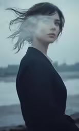 a woman in black poses on the beach