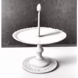 an empty cake stand with a single candle