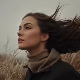 a woman is standing in a field with her hair blown up