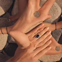 two women are holding their hands with two engagement rings on them