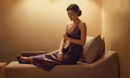 a woman wearing a gown is sitting on a couch