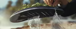 a person pouring water into a green planter