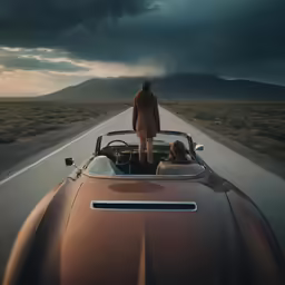 a woman riding in a convertible car down a road