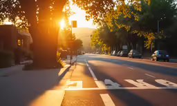 the sun is setting over the road with many cars parked on the side