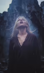 a woman is standing in a dark place with her eyes closed and there are trees around her