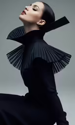 a woman wearing a black dress posing for the camera