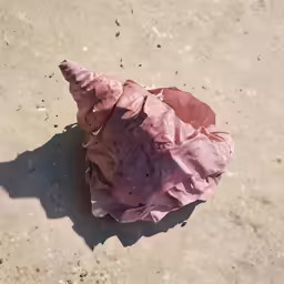 an origami paper piece sitting on top of sand