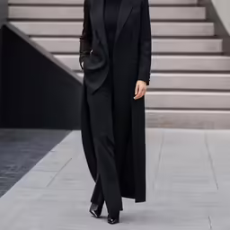 a woman in a black suit is walking down the street