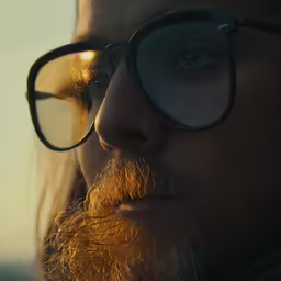 a man with glasses looks into the distance