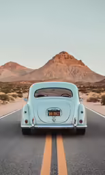 a blue car on the road with mountains in the background