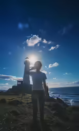a woman looking at a light house near the ocean