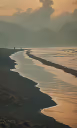 three people walking on the shore near the ocean