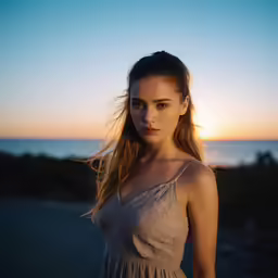 a woman in a dress posing on a road near the ocean