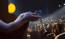 a hand with several nails holding a glass at a concert
