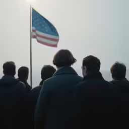 there is a man with his back turned in front of the american flag