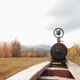 a clock sitting on top of an old train track in the mountains