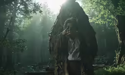 a man is in the woods talking on his cell phone