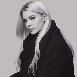 the blonde woman is wearing a black coat and a black scarf