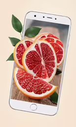 a cell phone with blood oranges arranged in half and placed next to it