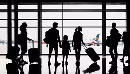 silhouettes of people carrying luggage at the airport,silhouettes of travelers with their luggage by an airport window