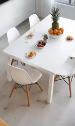 a white dining room table with fruit on it