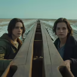 two woman looking down a railroad line and in the distance
