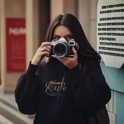 a woman holding a camera and taking photos of a building