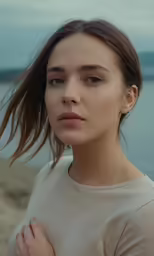 a beautiful woman with brown hair standing by the ocean