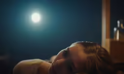 a woman lying on top of a bed with a light on