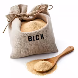 a scoop of flour on a wooden spoon beside a bag of bread