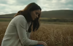 the girl sits on her knees in the middle of a large field