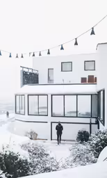 a white house has black windows and string lights