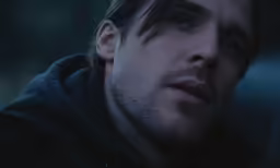 the man is staring ahead as he stands in the dark