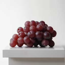 a pile of grapes on a white surface
