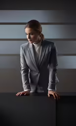a woman in a grey suit is holding a black box