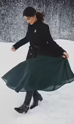 a woman with long skirt on standing in the snow