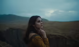 a woman in yellow is standing on the top of a hill