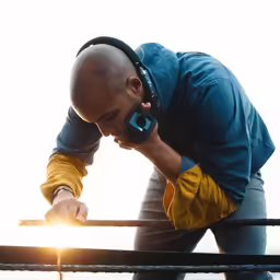 man with headphones leaning on rail and listening to music