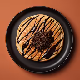 a black plate with a brown and white dessert covered in chocolate