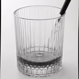 a shot glass on white with a silver toothbrush