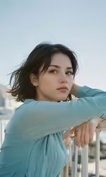a young woman leaning against the railing wearing a blue dress