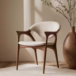 a chair sits next to a large vase and a flower