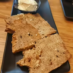 three crackers sit on a blue plate near dips