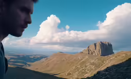 a man standing on top of a hill looking up at the sky