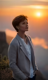 the woman is standing on the mountain looking at the sunset
