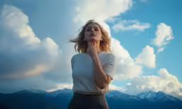 a woman in white shirt and tan skirt with a mountain range in the background